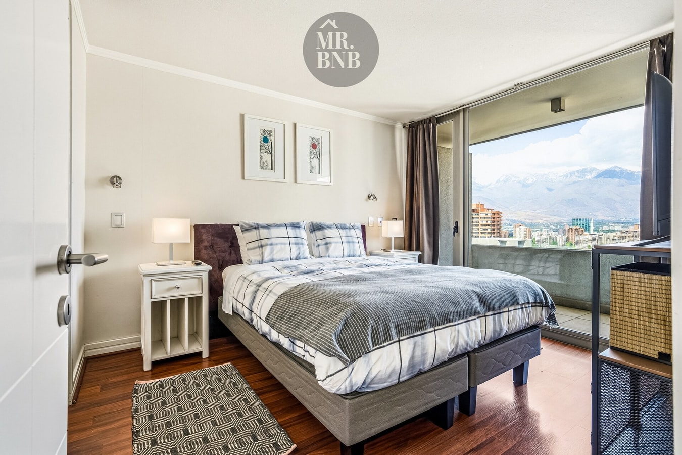 Dormitorio con cama, velador y ventanal con vista a la cordillera