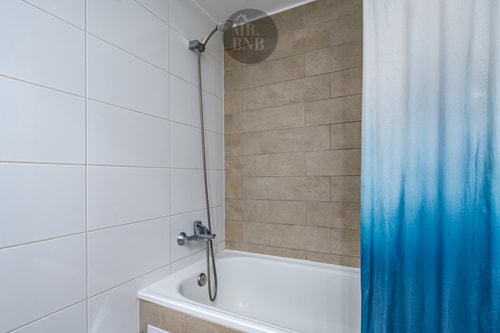 Tina con ducha y cortina azul degradé, azulejo beige de fondo