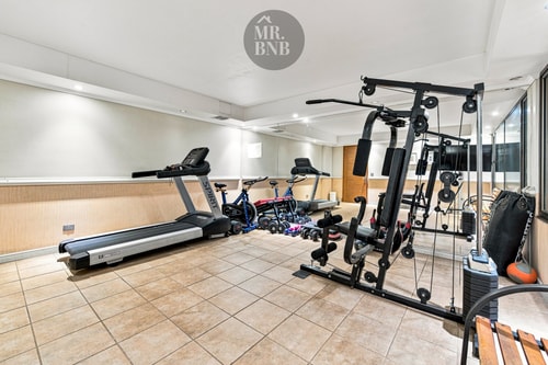 Gimnasio del edificio con trotadora, bicicletas estáticas y multiestación