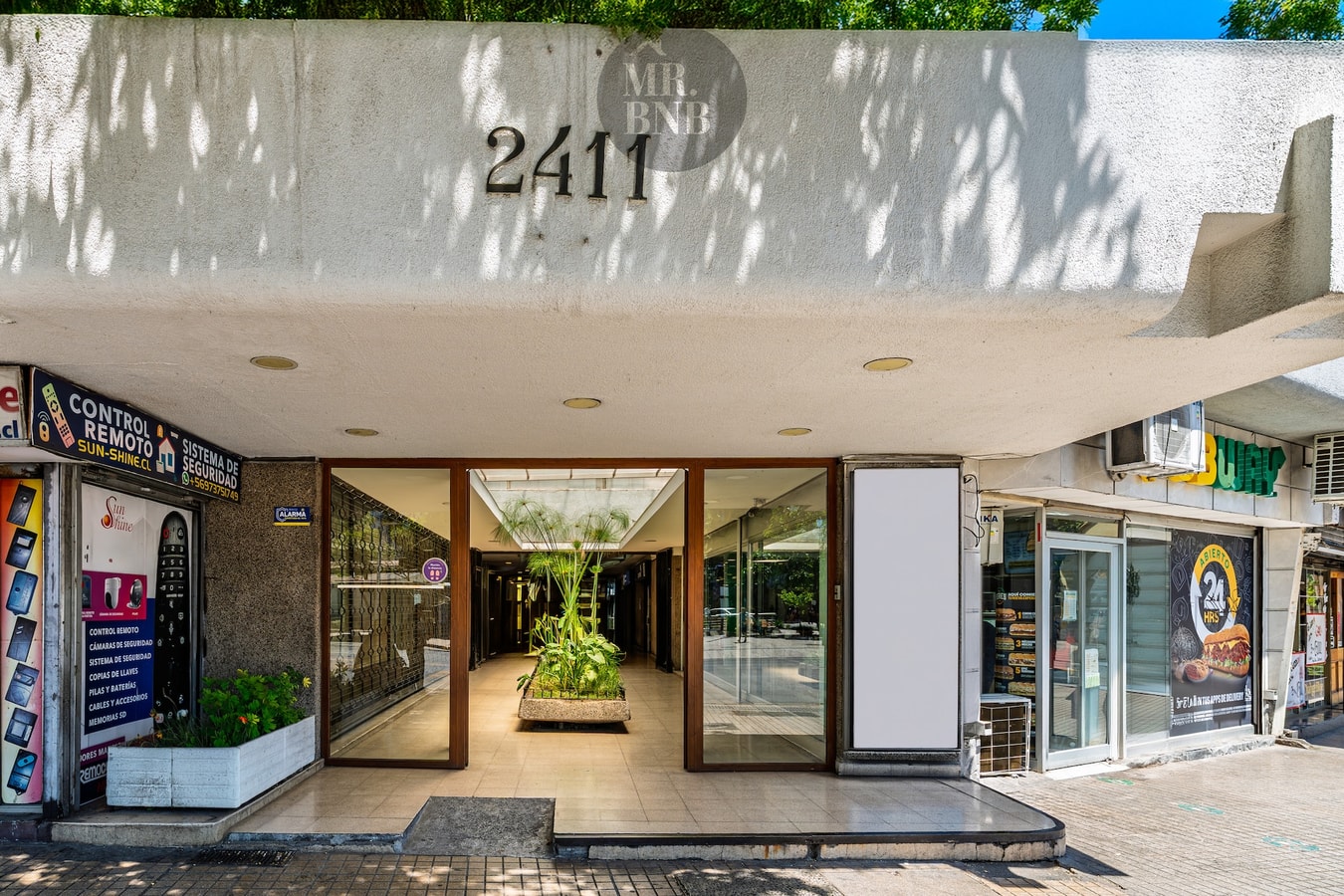 Fachada del edificio con acceso, número 2411 y locales comerciales