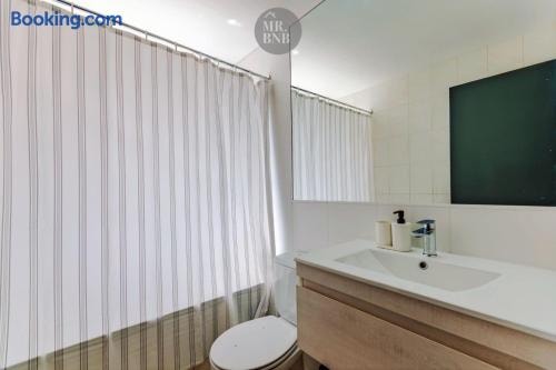 Baño con lavamanos, cortina de ducha a rayas y espejo oscuro.