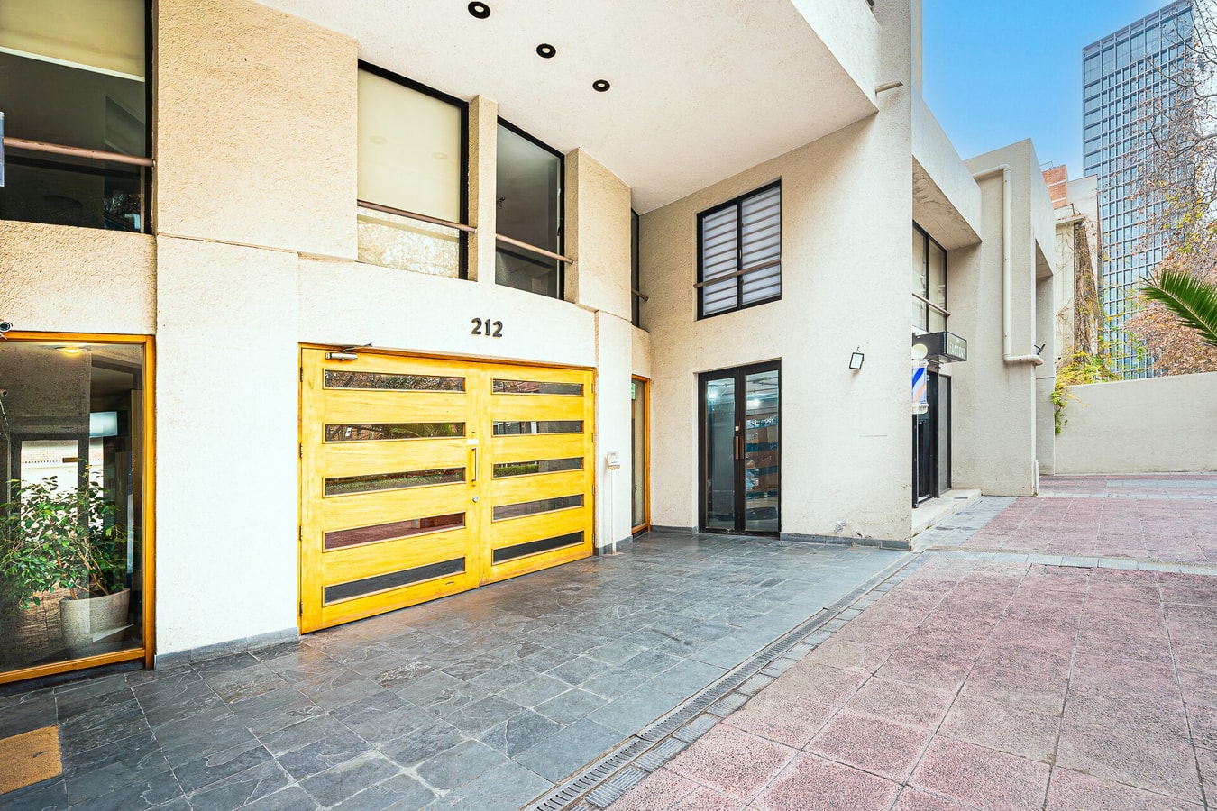 Fachada de acceso del edificio, con puerta corredera color amarillo y número 212