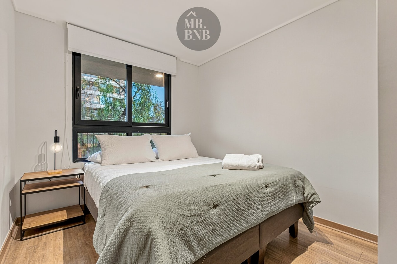 Dormitorio con cama doble, velador y ventana hacia la calle