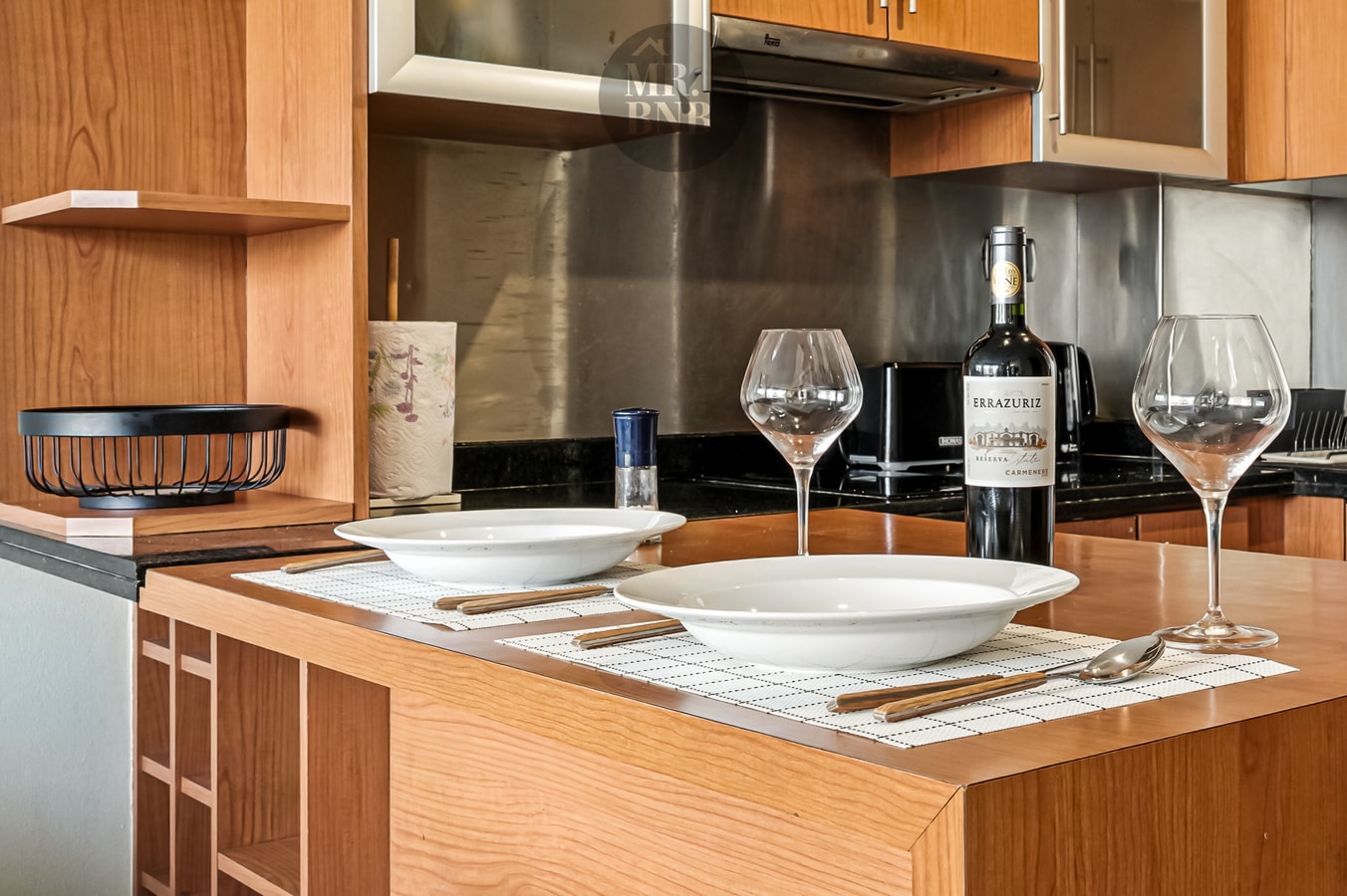 Detalle de barra de cocina con vajilla, copas de vino y botella