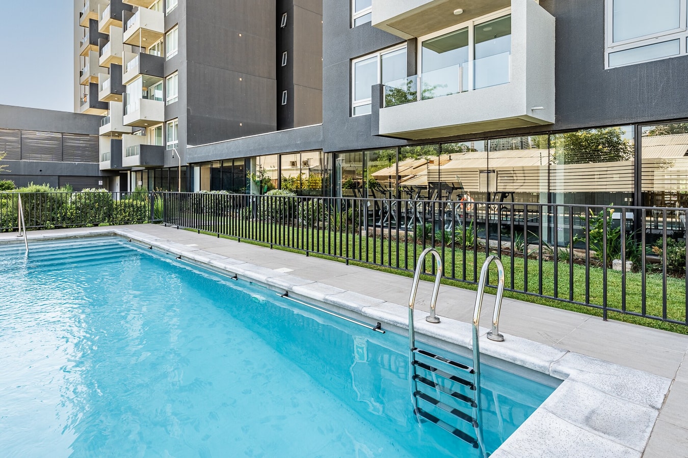 Piscina del edificio con reja de seguridad y vista al edificio, en el primer piso.