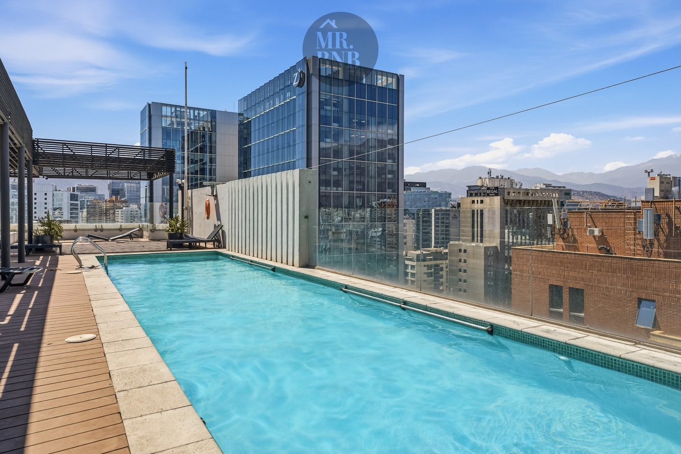 Piscina del edificio en la azotea, con deck y vista a los edificios circundantes.