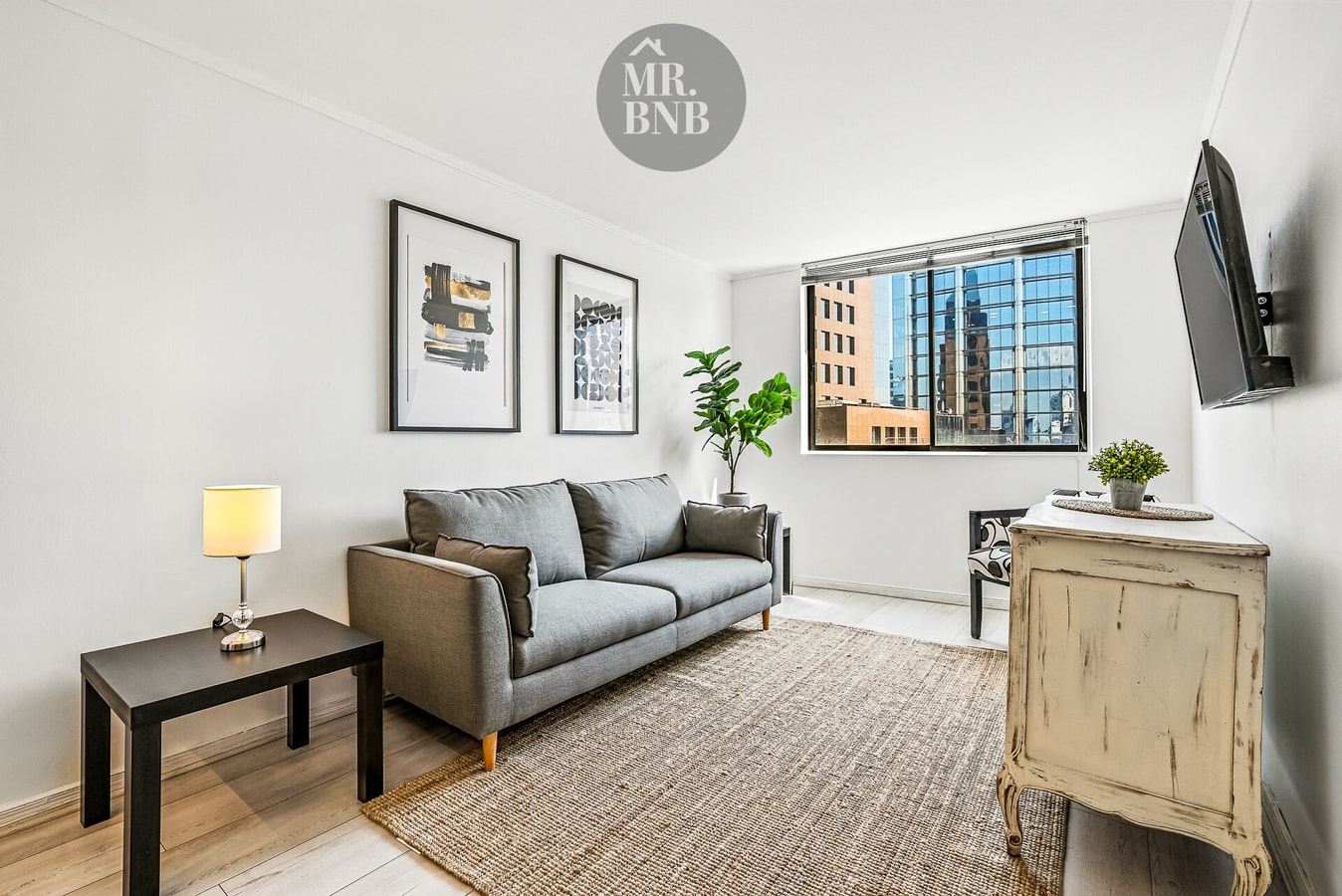 Living con dos sofás grises, mesa auxiliar y ventanal con vista a la ciudad