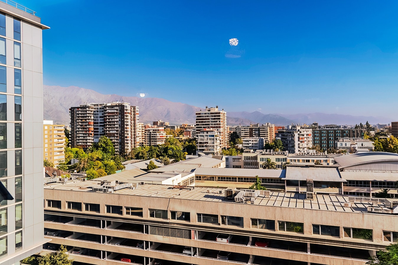 Vista desde ventana hacia techos de edificios bajos y cerros al fondo