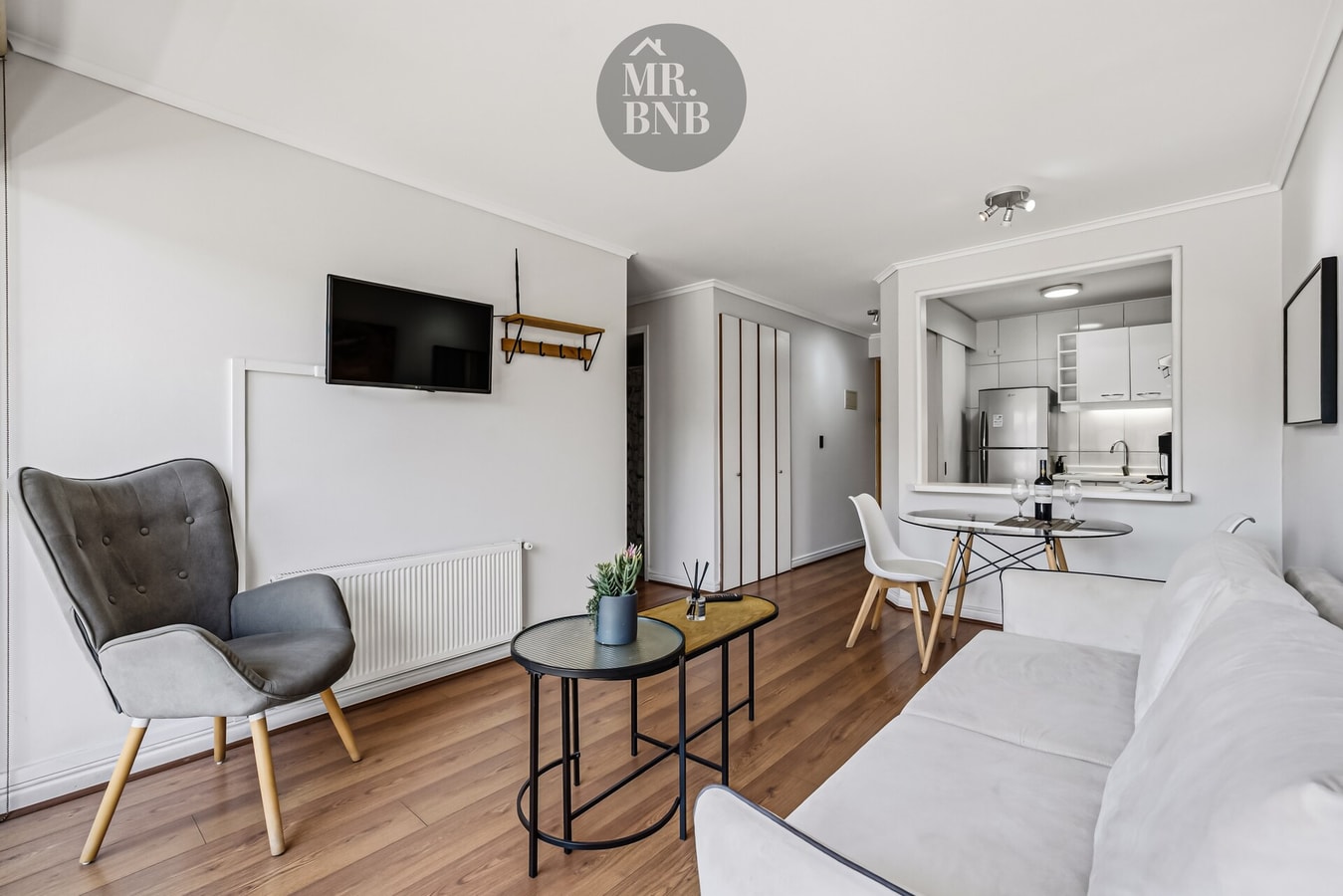 Living con sillón, mesa auxiliar y sofá, cocina y comedor al fondo.
