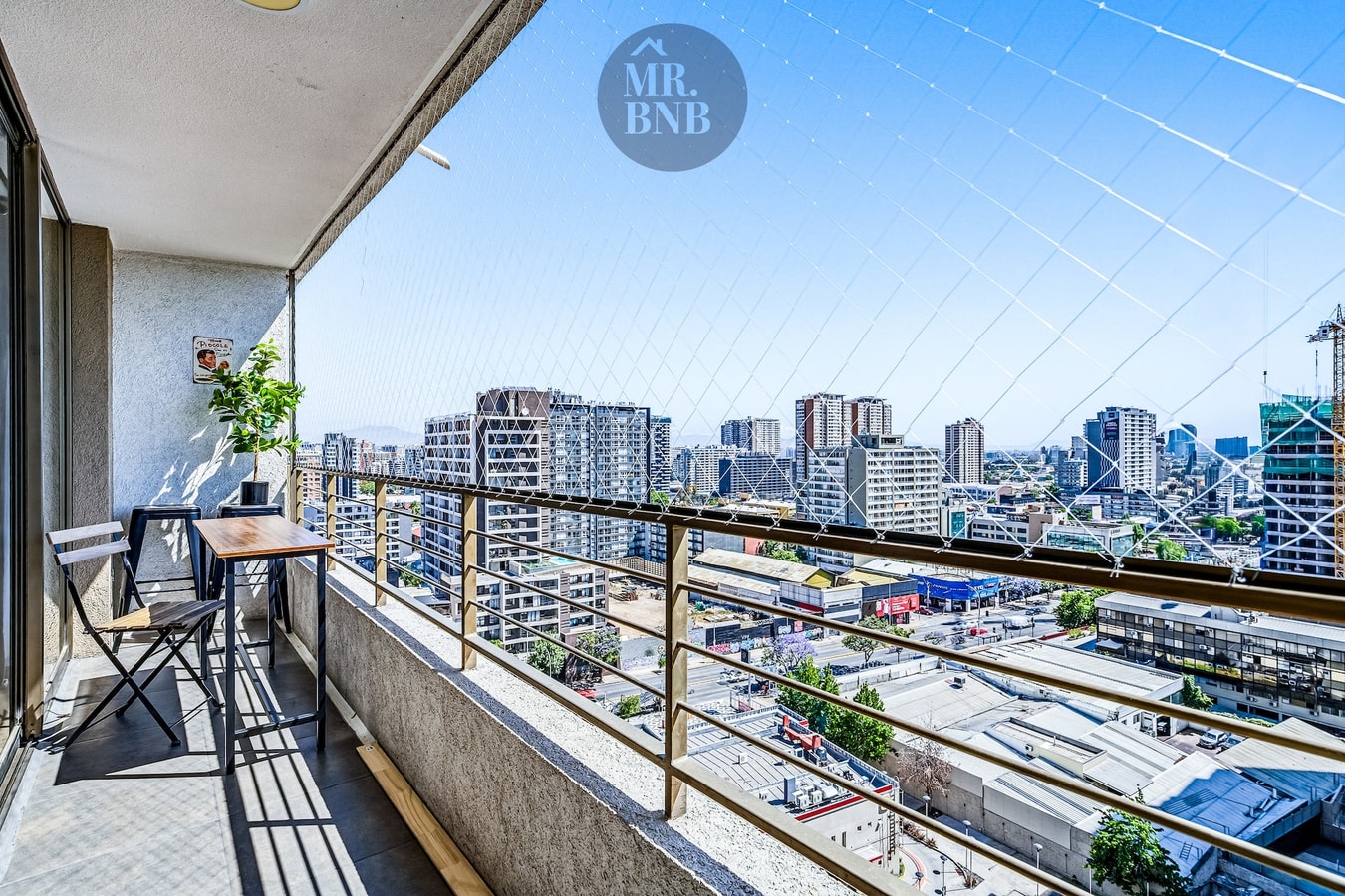 Balcón privado con silla, mesa baja y vista panorámica de la ciudad