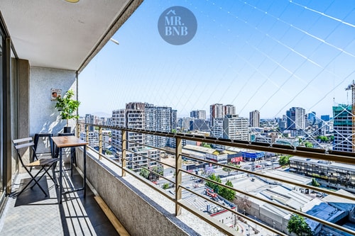 Balcón privado con silla, mesa baja y vista panorámica de la ciudad