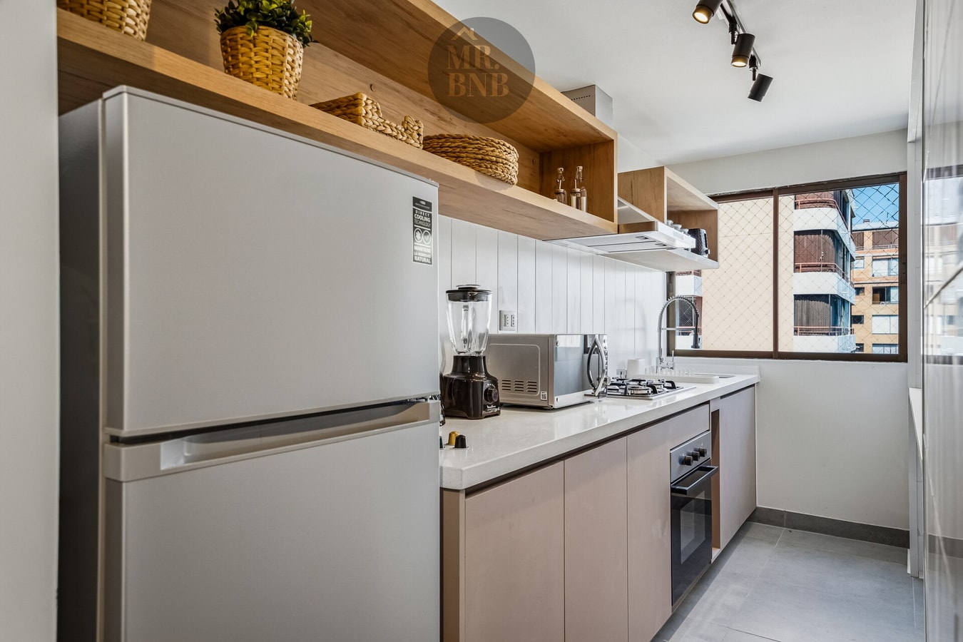 Cocina con refrigerador, repisas de madera abiertas y ventana lateral