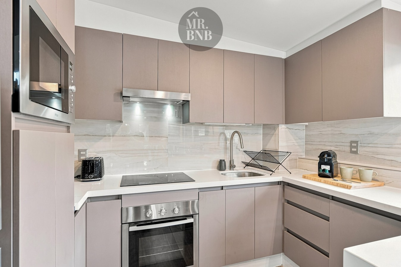 Cocina con muebles color arena, cocina eléctrica y campana
