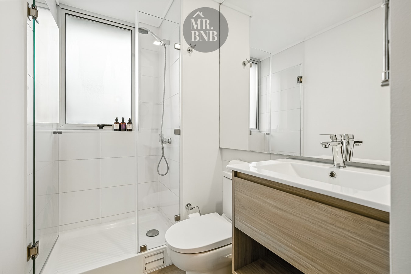 Baño con ducha de vidrio, tina, lavamanos con mueble de madera e inodoro