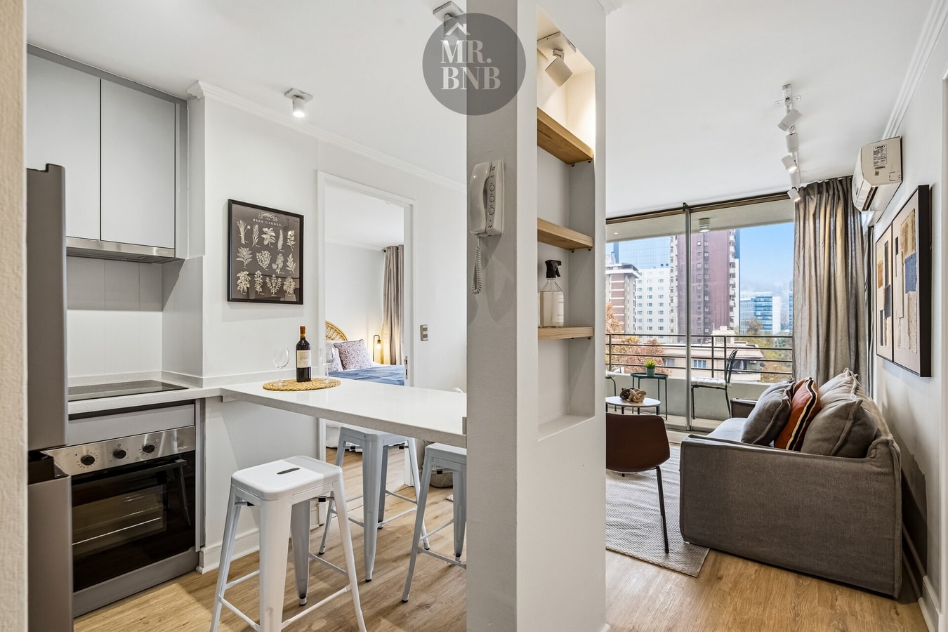 Barra de cocina con banquetas altas, con vista hacia el living y ventanal con balcón