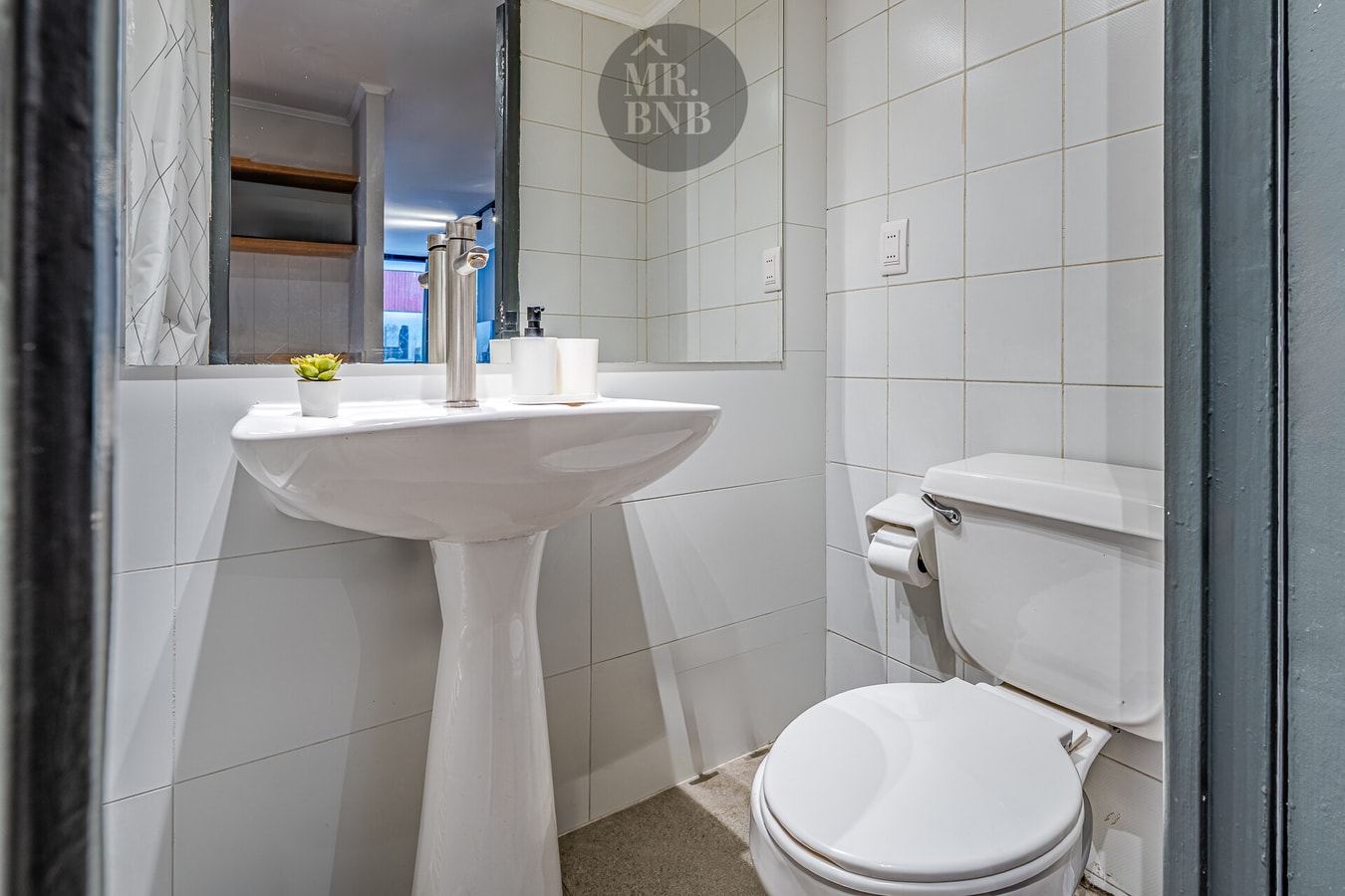 Baño con lavamanos pedestal, inodoro, espejo y repisa