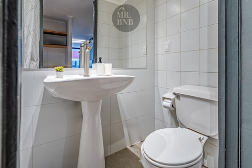 Baño con lavamanos pedestal, inodoro, espejo y repisa