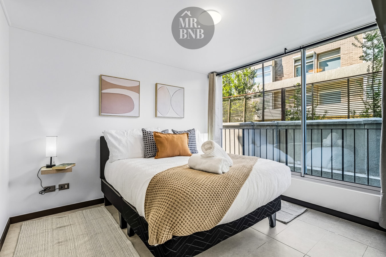 Dormitorio con cama de dos plazas, toallas dobladas al centro, ventanal y la terraza a la vista