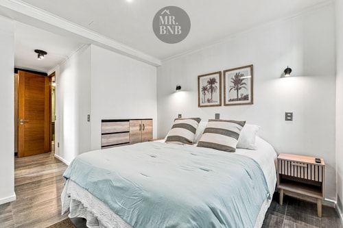 Dormitorio con cama, cojines y cuadros sobre el respaldo