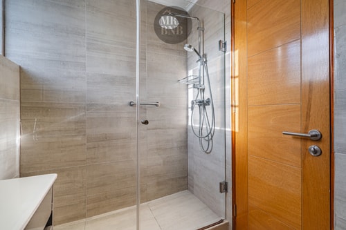 Baño con ducha de vidrio, azulejo y toalla