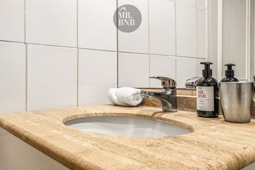 Detalle del lavamanos de mármol del baño, con grifería y dispensadores de jabón