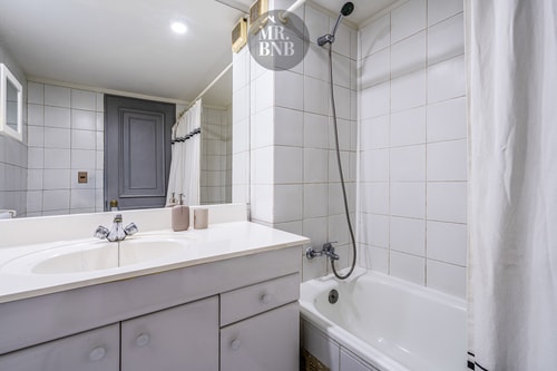 Baño con tina, ducha telefono y lavamanos gris