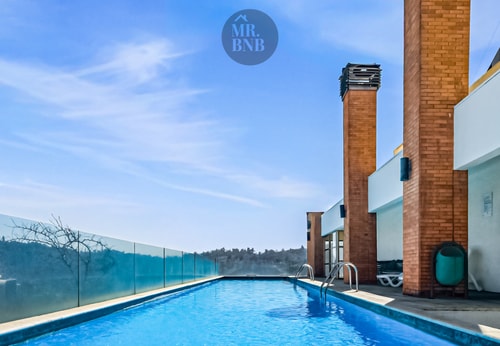 Piscina en azotea del edificio con vista a la cordillera y estructuras del edificio