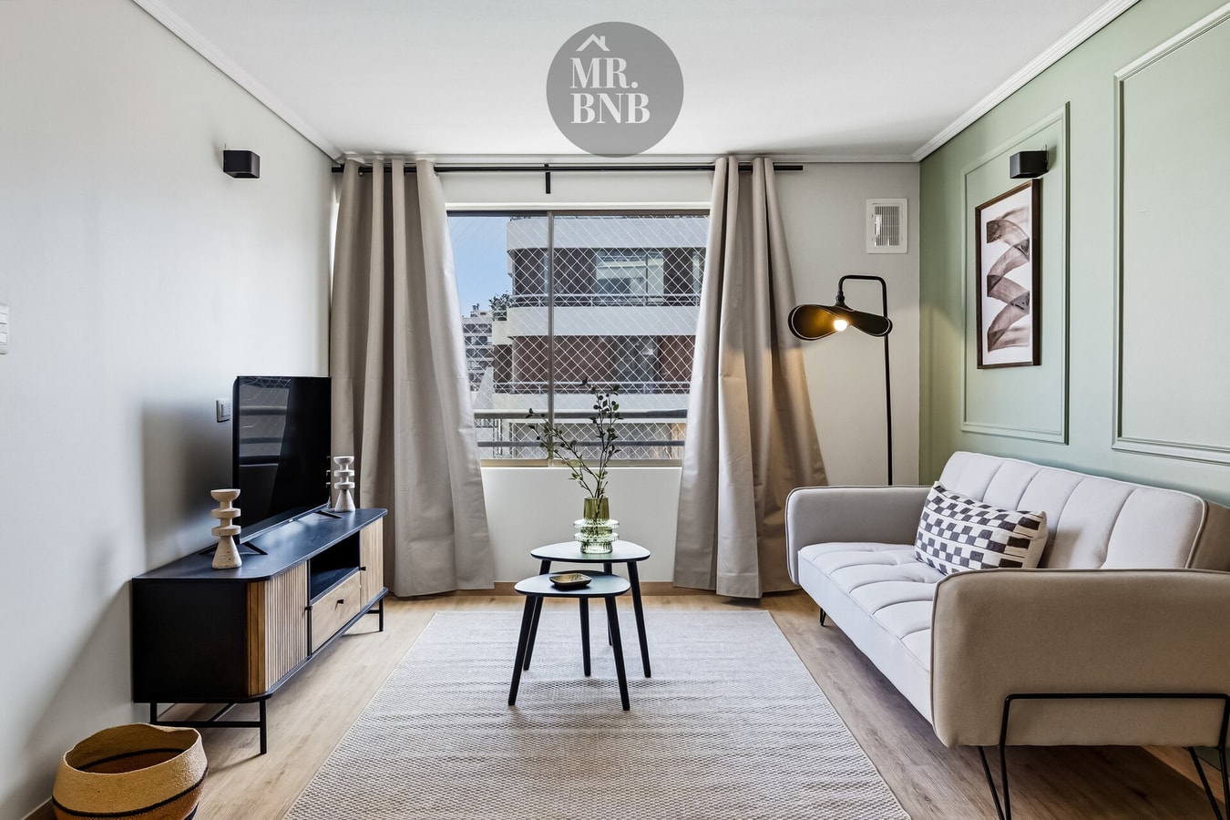 Living con sofá gris, mueble de TV y ventana con cortinas