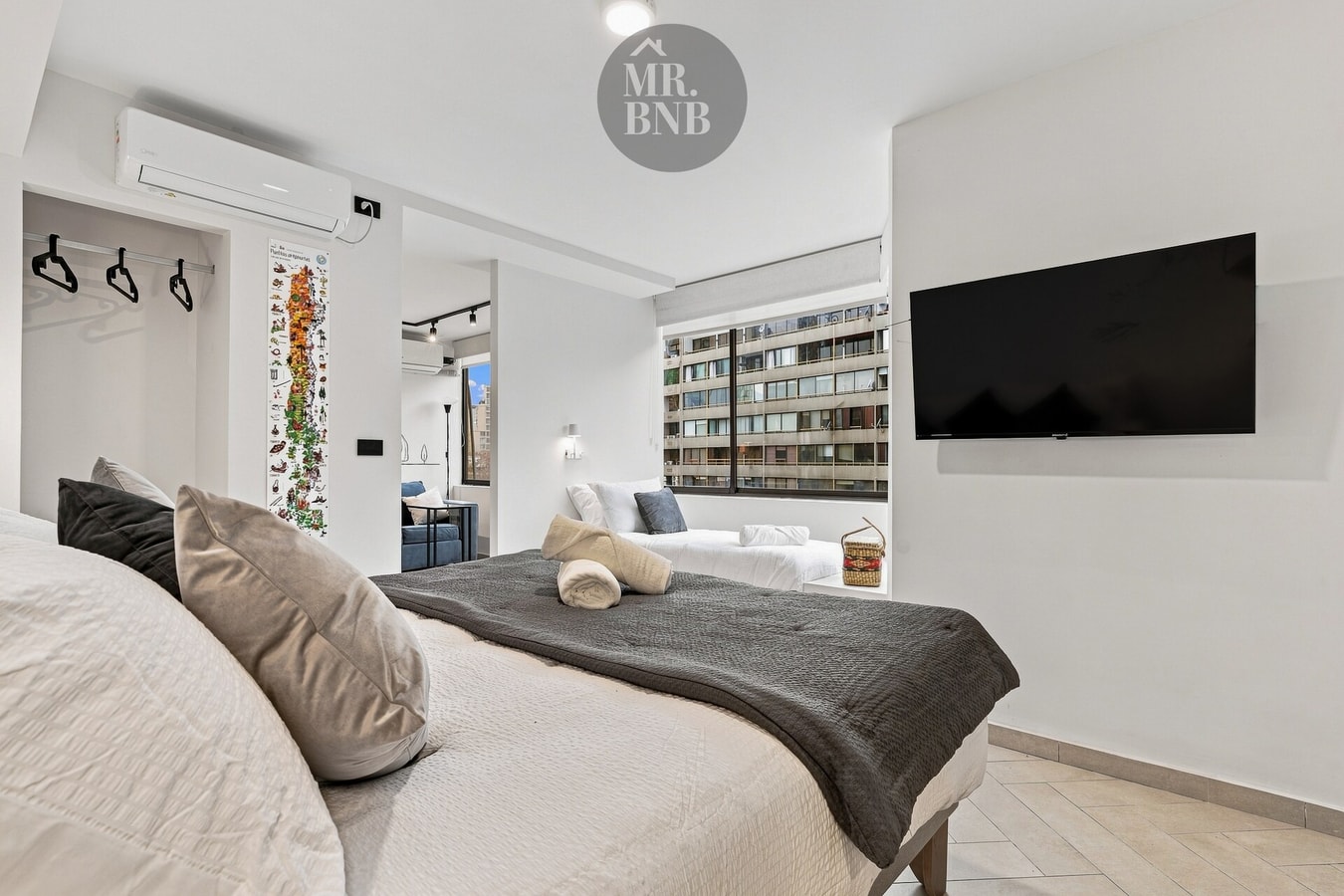 Dormitorio con cama, televisor en la pared y aire acondicionado split.