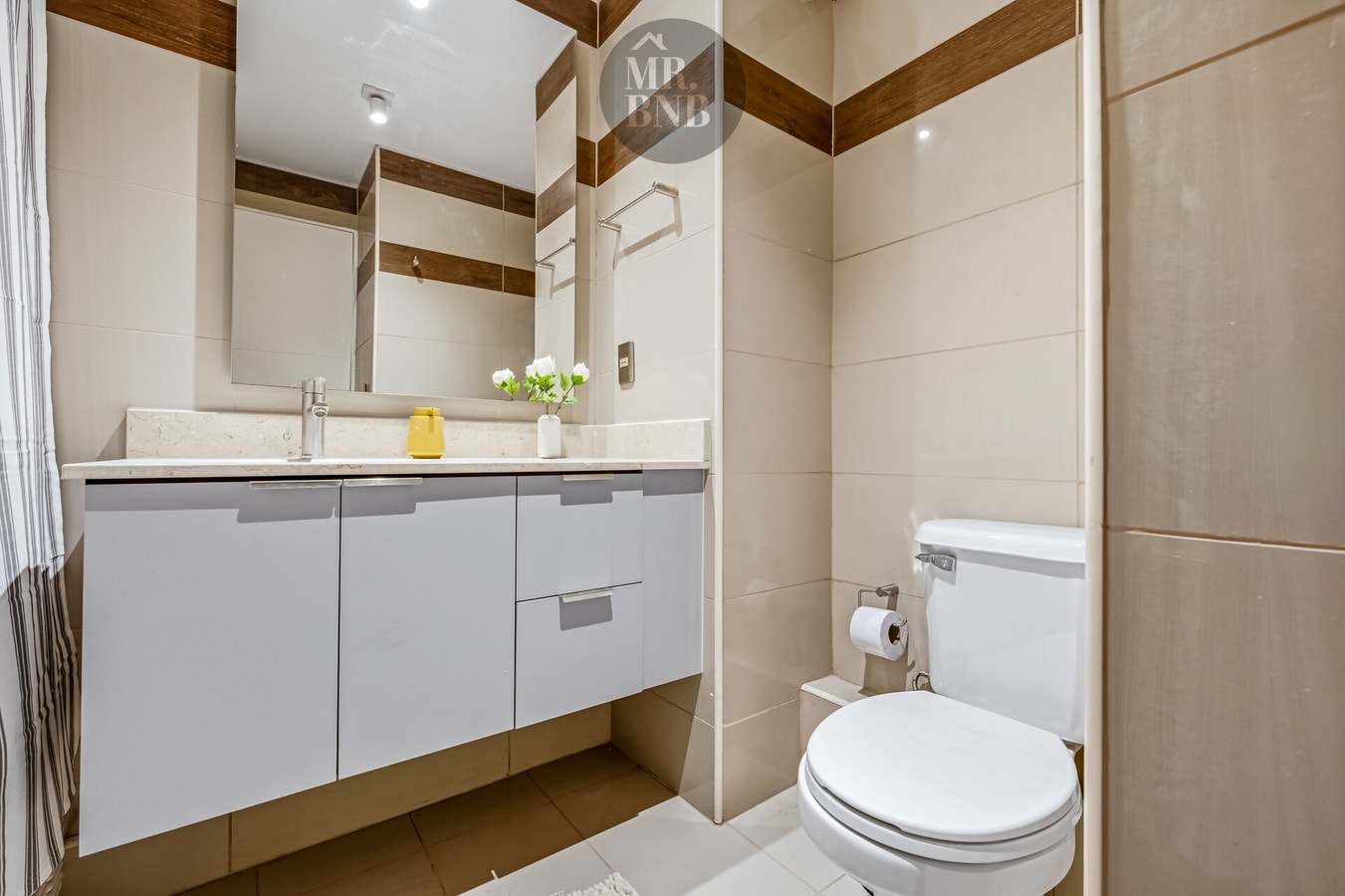Baño con mueble vanitorio blanco, espejo e inodoro
