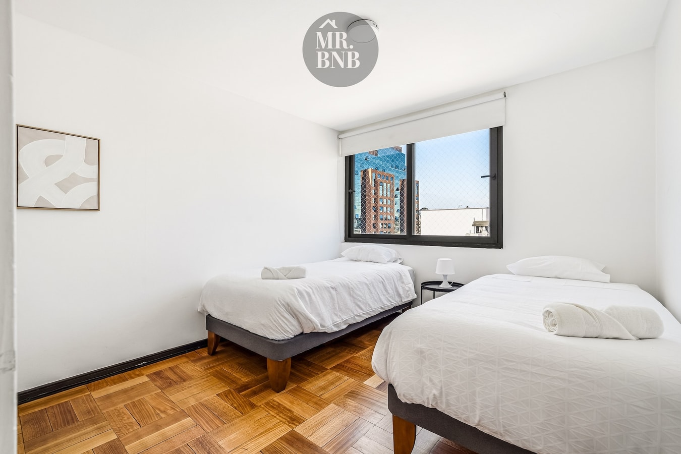 Dormitorio con dos camas individuales y ventana con vista a edificios