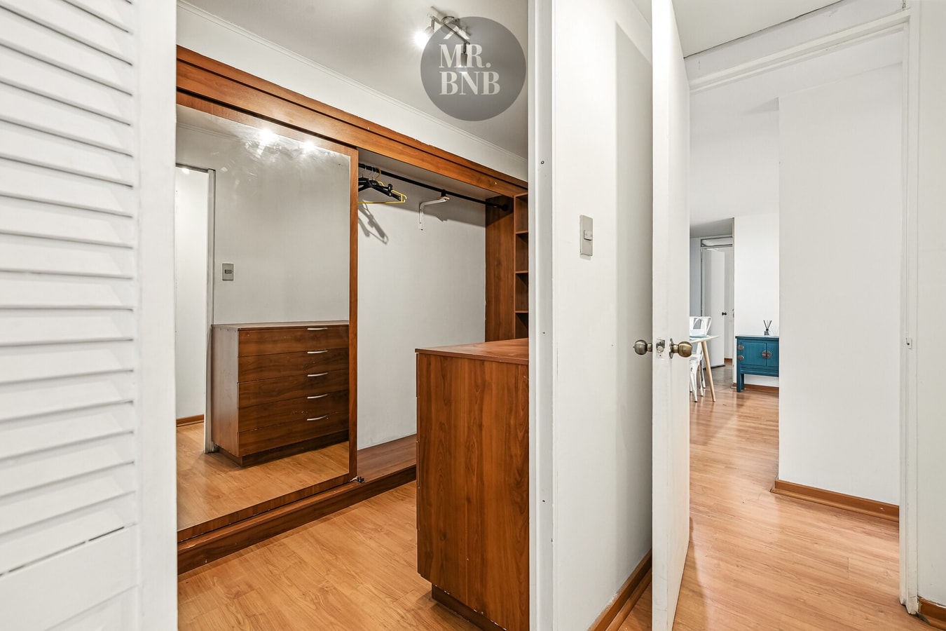 Vestidor con cómoda de madera, espejo y closet abierto