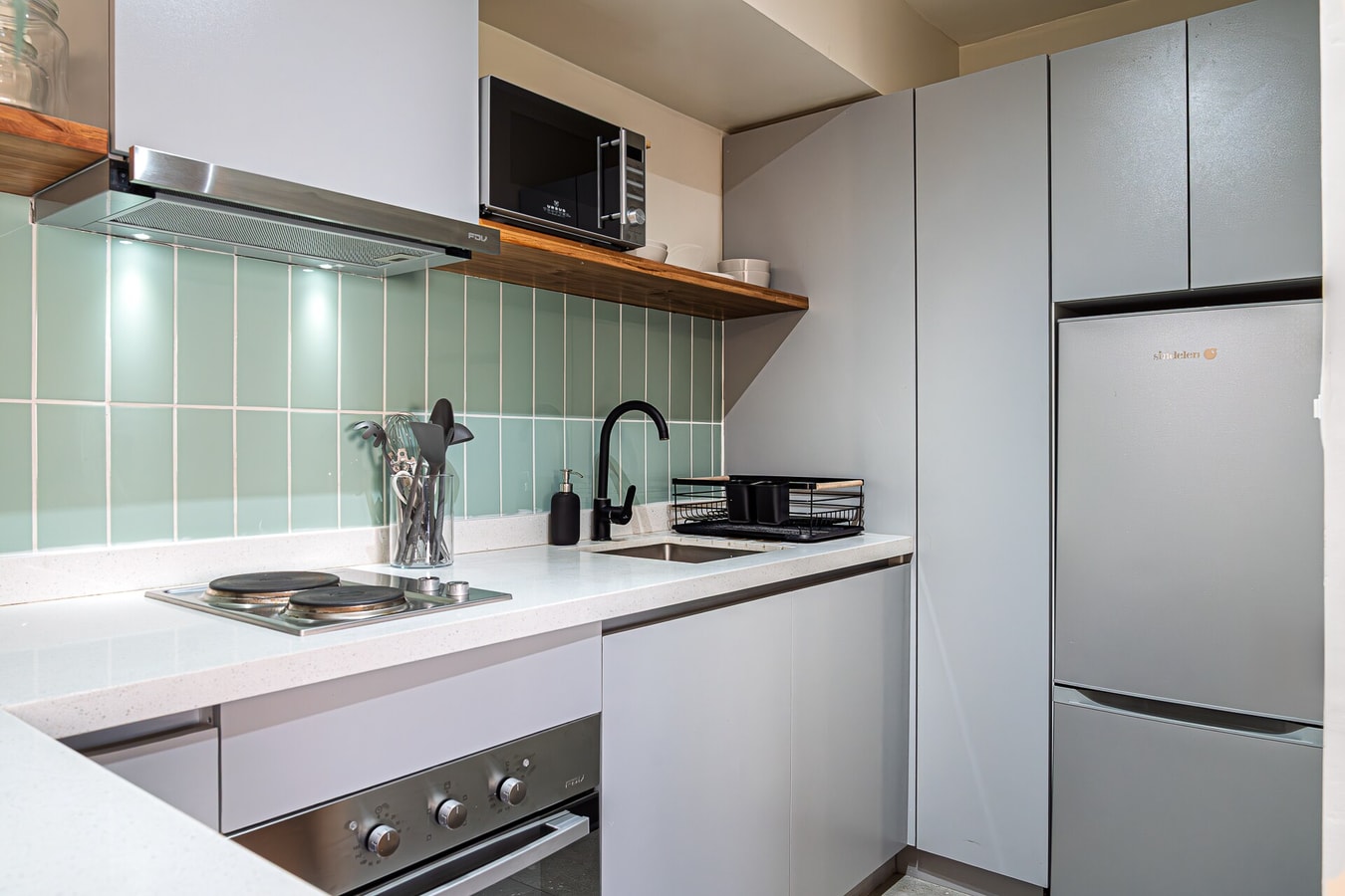 Cocina blanca con cocinilla, horno, campana y revestimiento en cerámica verde clara
