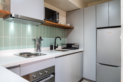 Cocina blanca con cocinilla, horno, campana y revestimiento en cerámica verde clara