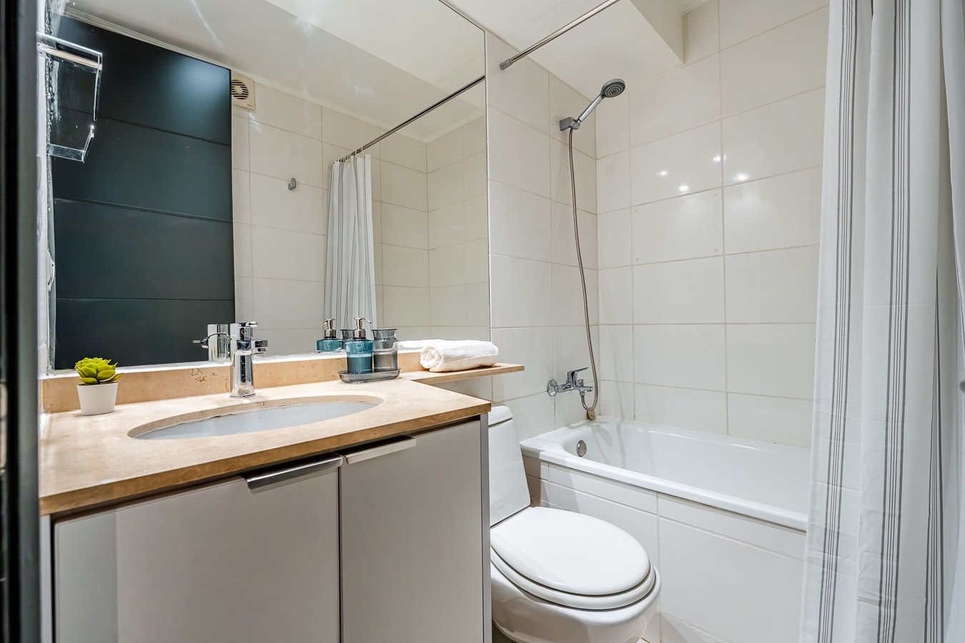 Baño con tina, ducha, mueble vanitorio y amenities