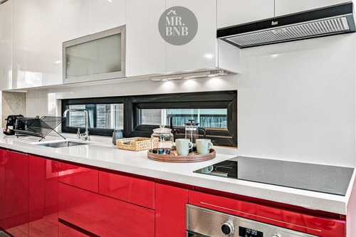 Cocina roja con campana extractora y mesón blanco