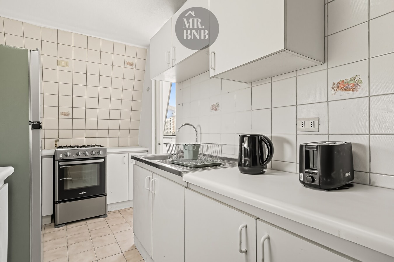 Cocina con muebles blancos, cocina a gas, hervidor y tostador