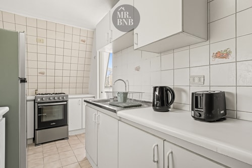 Cocina con muebles blancos, cocina a gas, hervidor y tostador