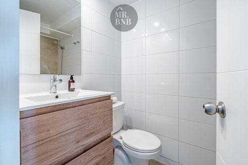 Baño con mueble vanitorio de madera, lavamanos, inodoro y espejo grande