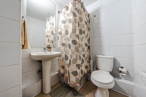 Baño con cortina floral, lavamanos, inodoro y tina