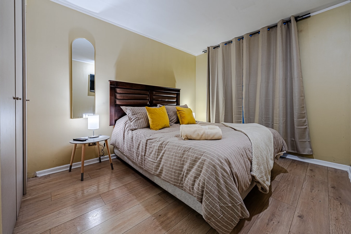 Dormitorio con cama, arco decorativo y cubrecama a rayas mostaza