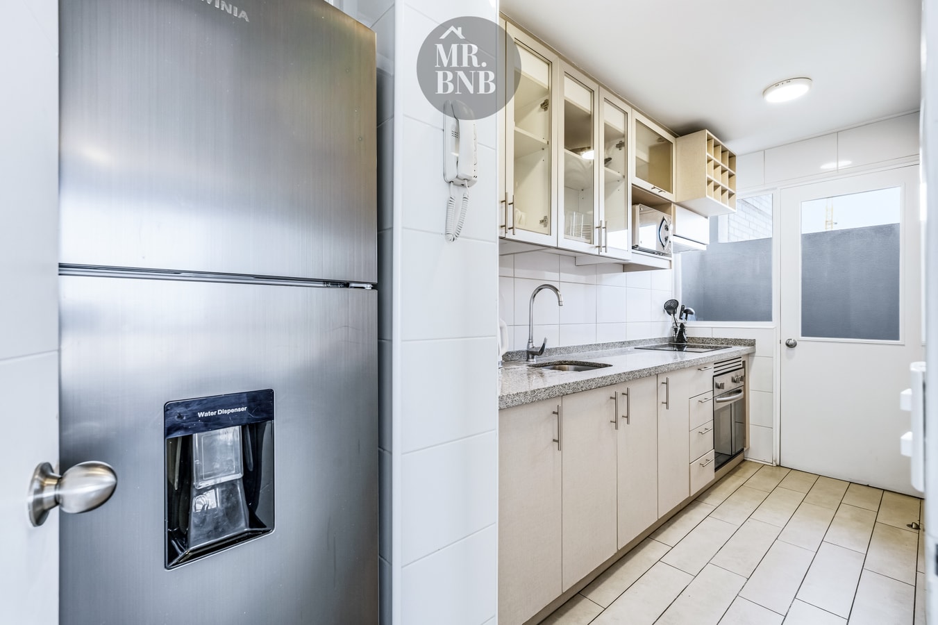 Cocina con refrigerador, muebles, lavaplatos y puerta con pasa mascotas