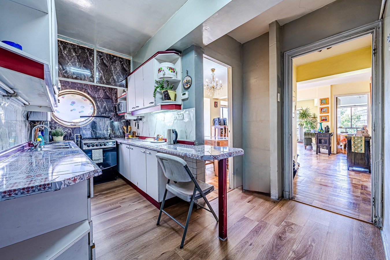 Cocina equipada con cocina a gas, mesón, silla plegable y acceso al living