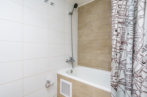Baño con tina, ducha con cortina estampada con mapa de ciudad e inodoro.