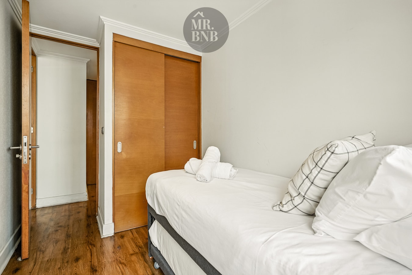 Dormitorio con cama individual, closet de madera y puerta de acceso