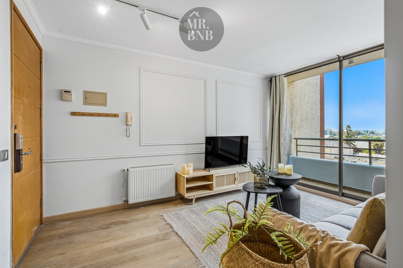 Hall de entrada con mueble de TV y ventanal hacia balcón con vista a la ciudad