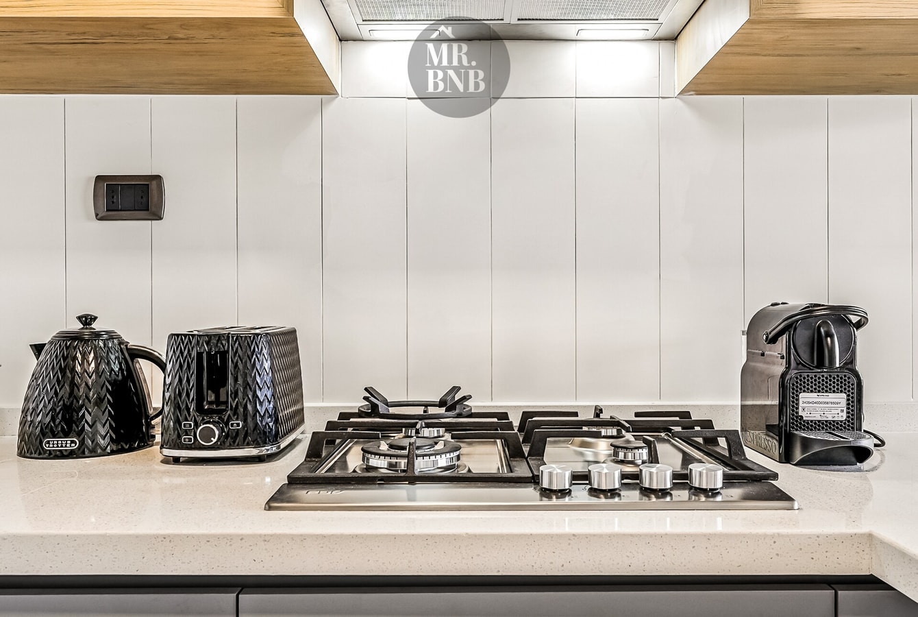 Mesón de cocina con hervidor, tostadora, cocina a gas y cafetera.