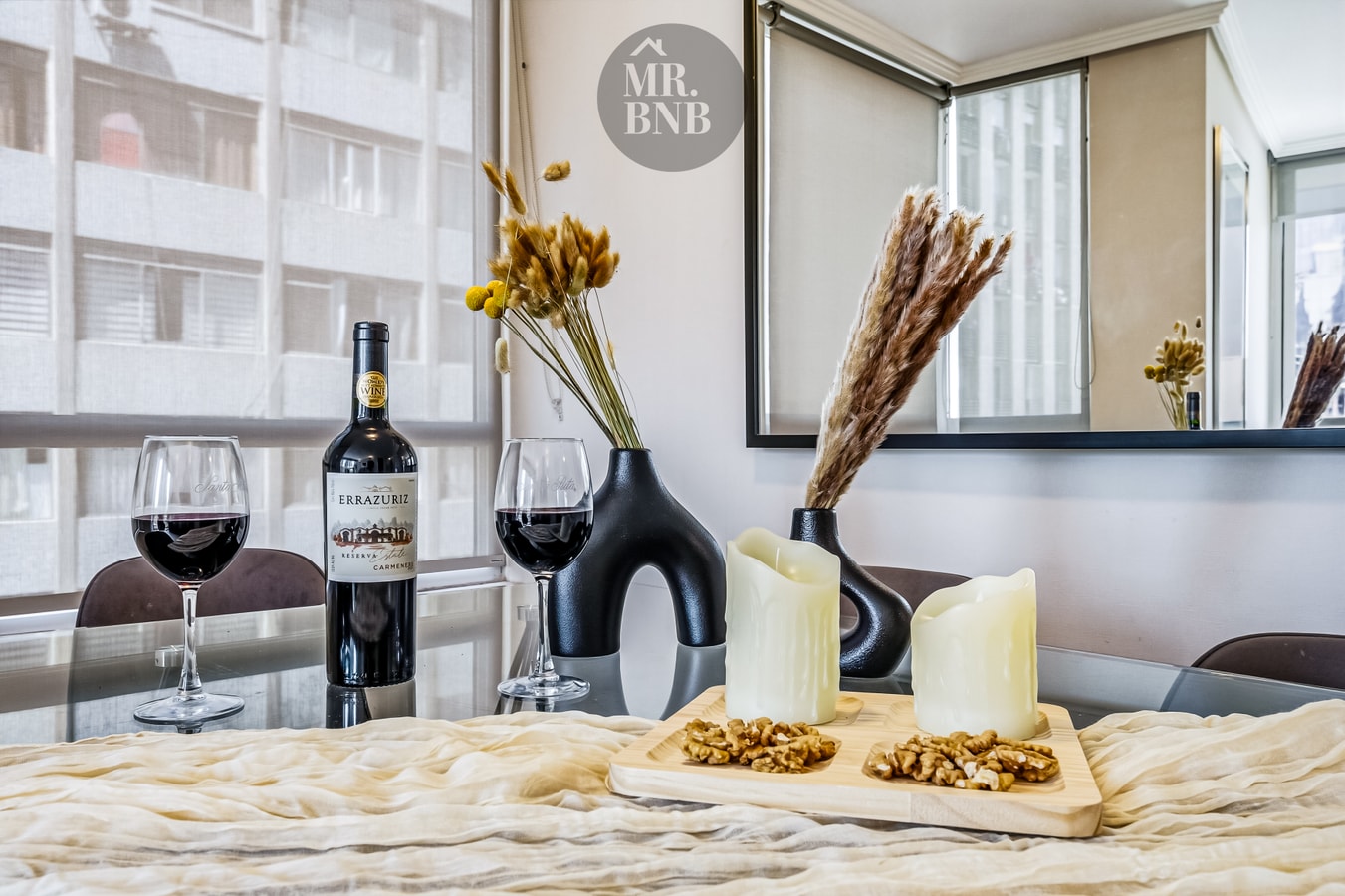Detalle de mesa con copas de vino, botella y flores decorativas.