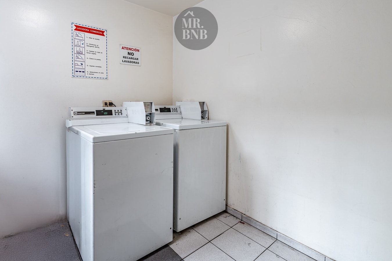 Sala de lavandería del edificio con dos lavadoras y aviso de no interrumpir el ciclo