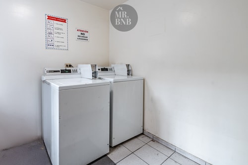Sala de lavandería del edificio con dos lavadoras y aviso de no interrumpir el ciclo